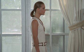 Movie still from “The Swimming Pool” (1969), directed by Jacques Deray – A woman in a white dress standing in front of a window; Medium shot, Low angle