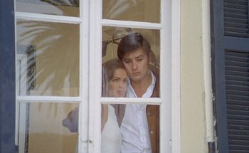 Movie still from “The Swimming Pool” (1969), directed by Jacques Deray – A man and a woman looking out of a window; Medium shot, Low angle