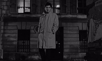 Movie still from “The Truth” (1960), directed by Henri-Georges Clouzot – A black and white photo of a man standing in front of a building; Medium shot, High angle