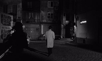 Movie still from “The Truth” (1960), directed by Henri-Georges Clouzot – A man in a trench coat walking down a street; Wide shot, High angle