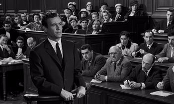 Movie still from “The Truth” (1960), directed by Henri-Georges Clouzot – An old photo of a man standing in front of a group of people; Medium shot, High angle