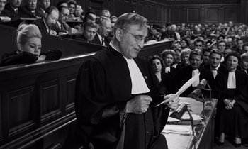 Movie still from “The Truth” (1960), directed by Henri-Georges Clouzot – An old man in a courtroom holding a paper; Medium shot, Low angle