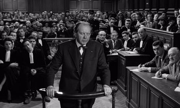Movie still from “The Truth” (1960), directed by Henri-Georges Clouzot – An old photo of a man standing in front of a crowd; Medium shot, High angle