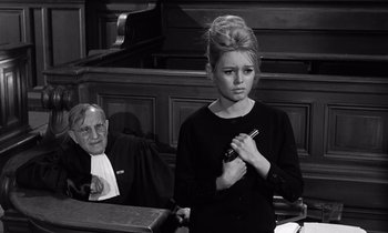 Movie still from “The Truth” (1960), directed by Henri-Georges Clouzot – A woman in a courtroom with a judge in the background; Medium shot, High angle