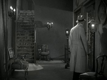 Movie still from “Ladies of Leisure” (1930), directed by Frank Capra – A black and white photo of a man in a coat and hat; Wide shot, High angle