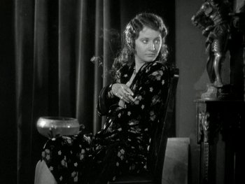 Movie still from “Ladies of Leisure” (1930), directed by Frank Capra – A woman sitting on a chair smoking a cigarette; Medium shot, Low angle