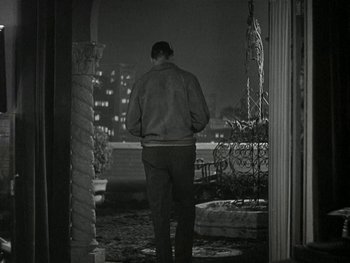 Movie still from “Ladies of Leisure” (1930), directed by Frank Capra – A man standing on a porch at night looking out the window; Wide shot, High angle