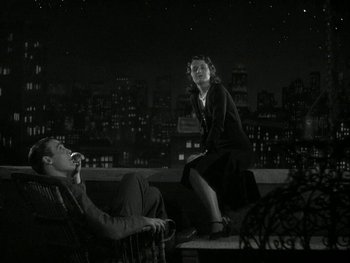 Movie still from “Ladies of Leisure” (1930), directed by Frank Capra – A man and a woman sitting on top of a wooden bench; Wide shot, High angle
