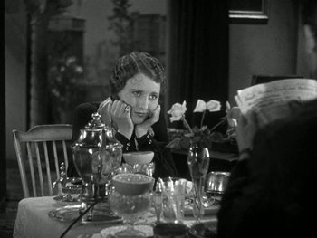 Movie still from “Ladies of Leisure” (1930), directed by Frank Capra – A woman sitting at a dinner table with her head resting on her hand; Medium shot, High angle