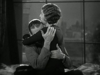 Movie still from “Ladies of Leisure” (1930), directed by Frank Capra – A man and a woman hugging each other in front of a window; Medium shot, High angle