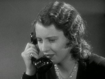 Movie still from “Ladies of Leisure” (1930), directed by Frank Capra – A woman talking on a phone while wearing a pearl necklace; Close Up shot, High angle
