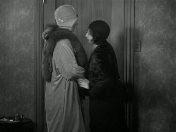 Movie still from “Ladies of Leisure” (1930), directed by Frank Capra – A couple of women standing next to each other in a room; Medium shot, Over the shoulder angle
