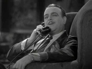 Movie still from “Ladies of Leisure” (1930), directed by Frank Capra – A black and white photo of a man talking on a phone; Close Up shot, High angle