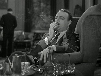 Movie still from “Ladies of Leisure” (1930), directed by Frank Capra – A black and white photo of a man smoking a cigarette; Medium shot, Low angle