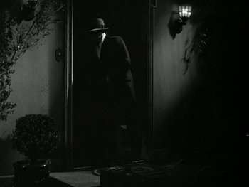 Movie still from “Ladies of Leisure” (1930), directed by Frank Capra – A man wearing a hat standing in front of an open door; Wide shot, Low angle