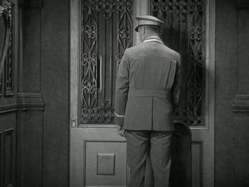 Movie still from “Ladies of Leisure” (1930), directed by Frank Capra – A man in a uniform standing in front of an open door; Wide shot, High angle
