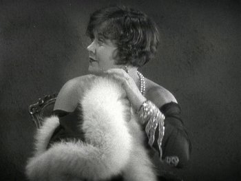 Movie still from “Ladies of Leisure” (1930), directed by Frank Capra – An old photo of a woman holding a fur coat; Medium shot, Low angle