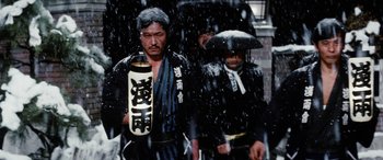 Movie still from “Lady Snowblood” (1973), directed by Toshiya Fujita – Two men walking in the rain holding umbrellas; Medium shot, Low angle