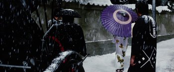 Movie still from “Lady Snowblood” (1973), directed by Toshiya Fujita – Two people with umbrellas standing in the snow; Medium shot, Over the shoulder angle