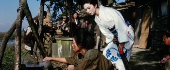 Movie still from “Lady Snowblood” (1973), directed by Toshiya Fujita – A man and a woman are sitting on the ground in front of a crowd of onlookers; Medium shot, Over the shoulder angle