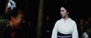 Movie still from “Lady Snowblood” (1973), directed by Toshiya Fujita – A woman standing in front of a tree with a man in the background; Medium shot, Over the shoulder angle