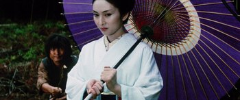 Movie still from “Lady Snowblood” (1973), directed by Toshiya Fujita – A geisha holding an open umbrella in front of a purple wall; Close Up shot, Low angle