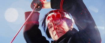 Movie still from “Lady Snowblood” (1973), directed by Toshiya Fujita – A woman with blood all over her face holding a sword; Close Up shot, Low angle