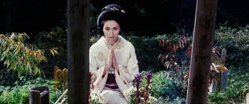 Movie still from “Lady Snowblood” (1973), directed by Toshiya Fujita – A geisha in a kimono is sitting in a garden; Medium shot, High angle