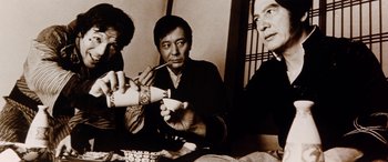 Movie still from “Lady Snowblood” (1973), directed by Toshiya Fujita – A group of people sitting at a table eating food; Medium shot, Low angle