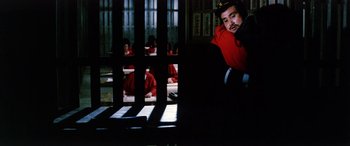Movie still from “Lady Snowblood” (1973), directed by Toshiya Fujita – A man sitting on a chair in a room; Medium shot, Over the shoulder angle