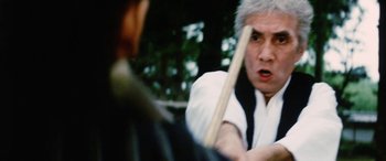 Movie still from “Lady Snowblood” (1973), directed by Toshiya Fujita – A man holding a baseball bat in front of another man; Close Up shot, Over the shoulder angle