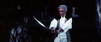 Movie still from “Lady Snowblood” (1973), directed by Toshiya Fujita – An older man holding a sword in a forest; Medium shot, Low angle