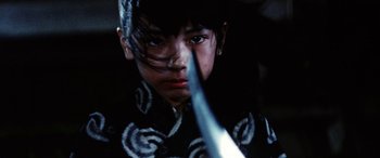Movie still from “Lady Snowblood” (1973), directed by Toshiya Fujita – A young man holding a sword in his hand; Close Up shot, Low angle