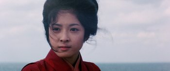 Movie still from “Lady Snowblood” (1973), directed by Toshiya Fujita – A young woman in a red dress is looking at the camera; Close Up shot, Low angle