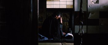 Movie still from “Lady Snowblood” (1973), directed by Toshiya Fujita – A man sitting on the ground in front of an open window; Medium shot, Over the shoulder angle