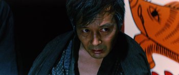 Movie still from “Lady Snowblood” (1973), directed by Toshiya Fujita – A person wearing a black jacket; Close Up shot, Low angle