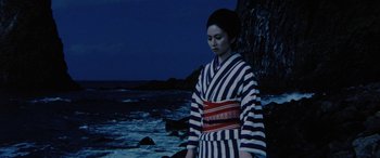 Movie still from “Lady Snowblood” (1973), directed by Toshiya Fujita – A woman in a striped kimono standing on the beach; Medium shot, Low angle