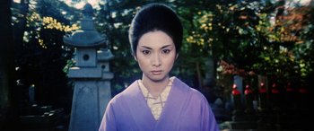 Movie still from “Lady Snowblood” (1973), directed by Toshiya Fujita – A young woman in a purple kimono is standing in front of a stone wall; Close Up shot, Low angle