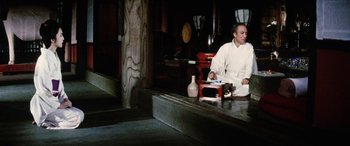 Movie still from “Lady Snowblood” (1973), directed by Toshiya Fujita – A man sitting on the ground with a book in his hands; Wide shot, Low angle