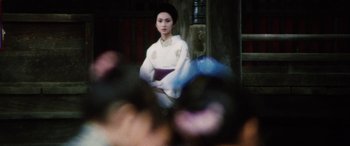 Movie still from “Lady Snowblood” (1973), directed by Toshiya Fujita – A woman in a white dress sitting on a chair; Medium shot, Over the shoulder angle