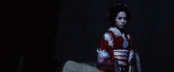Movie still from “Lady Snowblood” (1973), directed by Toshiya Fujita – A woman in a kimono sitting on a bench; Medium shot, Low angle