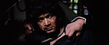 Movie still from “Lady Snowblood” (1973), directed by Toshiya Fujita – A man with blood all over his face holding a cross; Close Up shot, Low angle