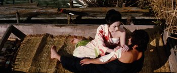 Movie still from “Lady Snowblood” (1973), directed by Toshiya Fujita – A woman in a kimono is sitting next to a man; Medium shot, High angle