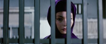 Movie still from “Lady Snowblood” (1973), directed by Toshiya Fujita – A woman in a purple hoodie behind a metal fence; Close Up shot, Low angle