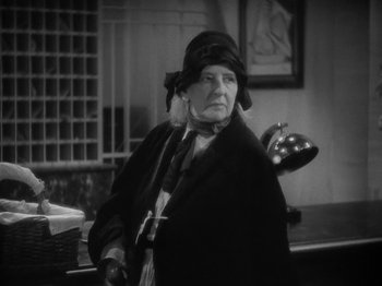 Movie still from “Lady for a Day” (1933), directed by Frank Capra – An older woman wearing a hat and holding an umbrella; Medium shot, Low angle