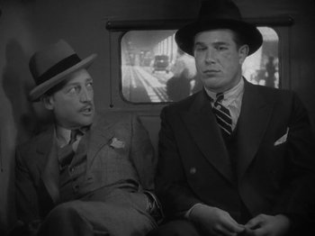 Movie still from “Lady for a Day” (1933), directed by Frank Capra – Two men in suits and hats sitting next to each other on a train; Medium shot, Low angle