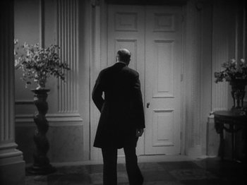Movie still from “Lady for a Day” (1933), directed by Frank Capra – A black and white photo of a man walking in front of an open door; Wide shot, Low angle
