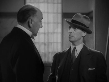 Movie still from “Lady for a Day” (1933), directed by Frank Capra – A man in a suit and a hat talking to another man in a suit and a hat; Medium shot, Low angle