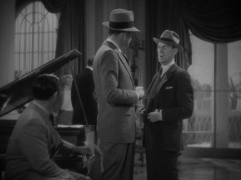 Movie still from “Lady for a Day” (1933), directed by Frank Capra – Two men in suits talking to each other in front of a piano; Medium shot, High angle