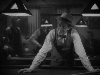 Movie still from “Lady for a Day” (1933), directed by Frank Capra – A man leaning over a pool table wearing a hat; Medium shot, High angle